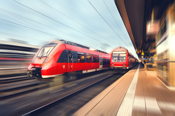 Wall Mural - Modern high speed red passenger trains at sunset. Railway statio