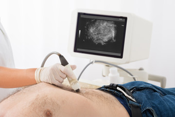 Doctor's Hand With Ultrasound Scan On Abdomen Of Male Patient