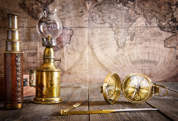 Wall Mural - Ship lamp, compass, divider and spyglass on the wood table. Travel and nautical theme grunge background. Retro style.