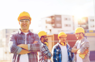 Canvas Print - group of smiling builders in hardhats outdoors