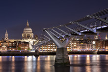 St Paul's Cathedral And The Millennium Bridge Over The Thames, At Night, With The Lights Shining On The Opposite Shore