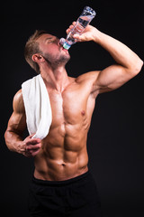 Wall Mural - young muscular man after training drinking water from the bottle