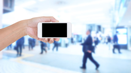 Hand holding mobile phone with blurred image of people use for b