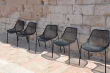 Empty Chairs In Row Under Stone Wall
