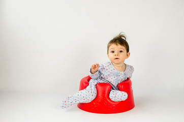 Canvas Print - cute baby girl sitting in a plastic seat