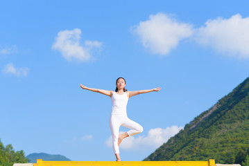 Young woman does yoga exercise outdoors.