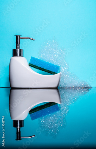 Fotografia, Obraz Tiny bath with a sponge and foam with reflection on a blue background