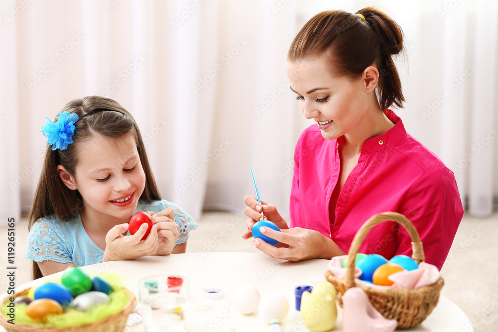 Mother and daughter painting eggs at Easter eve