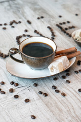 Wall Mural - Cup of coffee with grains, turkish delight and cinnamon sticks on wooden background