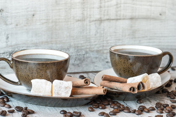 Cup of coffee with grains, turkish delight and cinnamon sticks on wooden background