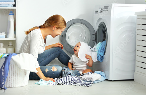 Cuadros en Lienzo mother a housewife with a baby fold clothes into the washing ma