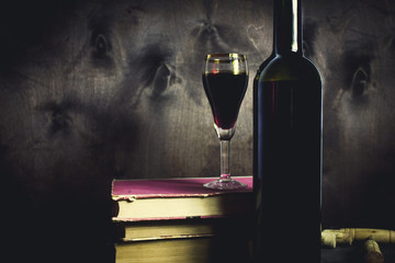 Red wine glass and old open book on wooden table