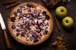 Homemade pie with apples and blackberry on dark stone background.