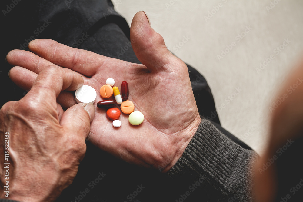 пожилой человек держит в руках таблетки
