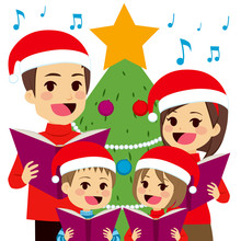 Happy Family Singing Carols In Front Of Christmas Tree At Home