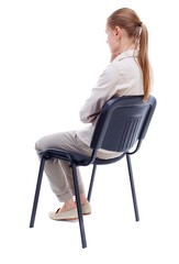 Wall Mural - back view of young beautiful woman sitting on chair. girl watching. Skinny girl in white denim suit sidit thoughtfully in his chair.