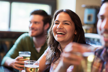 Wall Mural - happy woman with friends drinking beer at pub