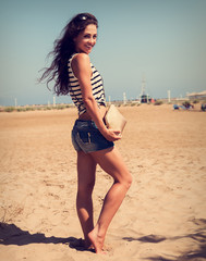 Beautiful smiling woman with fashion bag posing on the beach bac