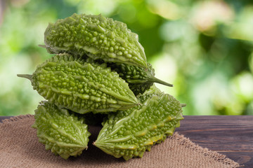 heap of bitter melon or momordica on wooden table with blurred background