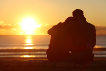 Couple Watching Sunset On The Beach In Winter