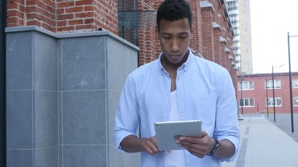walking black man and using tablet for browsing
