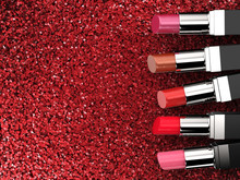 Many Shades Of Lipsticks On Red Glitter Background