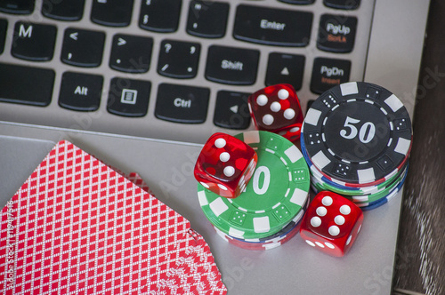 фотография Gambling chips and red dice on laptop keyboard background