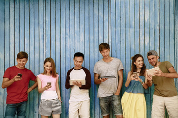 Wall Mural - Young people with gadgets on wooden planks background