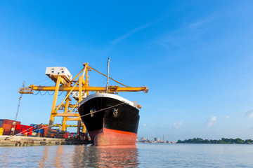 Container cargo freight ship with working crane loading bridge 