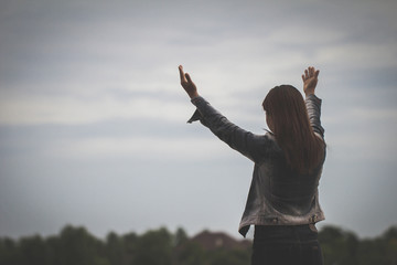 Women raised both hands up pray for blessings to God style Darke tones silhouette