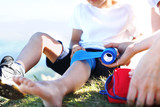 Fototapeta  - Bandażowanie nogi. Matka opatruje dziecięce kolano bandażem elastycznym.