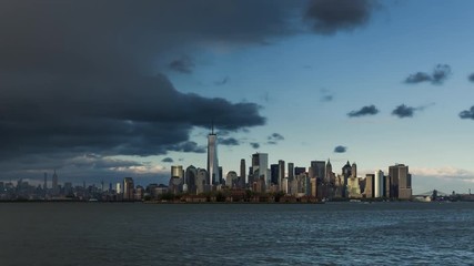 Fototapete - New York City Lower Manhattan cityscape time lapse video with afternoon storm, sunset and city lights at twilight. View of the Financial District skyscrapers, Midtown West and Ellis Island