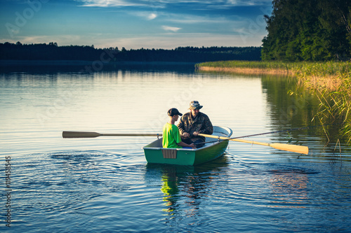 Fotografia father and son catch fish from a boat at sunset