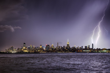 Wall Mural - Lightning hitting a New York City skyscraper at twilight. Stormy skies over Midtown West Manhattan from the Hudson River 
