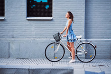 Happy Woman With Bike Standing Agains Brick Building