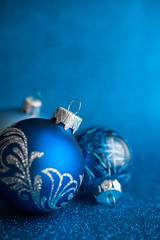 Wall Mural - blue xmas ornaments on dark blue glitter background with space for text. merry christmas card. winte