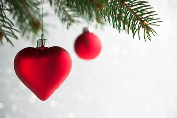 Wall Mural - red christmas ornaments (heart and ball) on the xmas tree on glitter bokeh background. winter holida