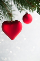 Wall Mural - red christmas ornaments (heart and ball) on the xmas tree on glitter bokeh background. winter holida