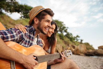 Wall Mural - Man playing guitar for his girlfriend sitting at the tent