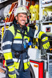 Feuerwehrmann in Uniform lehnt am Einsatzfahrzeug der Feuerwehr