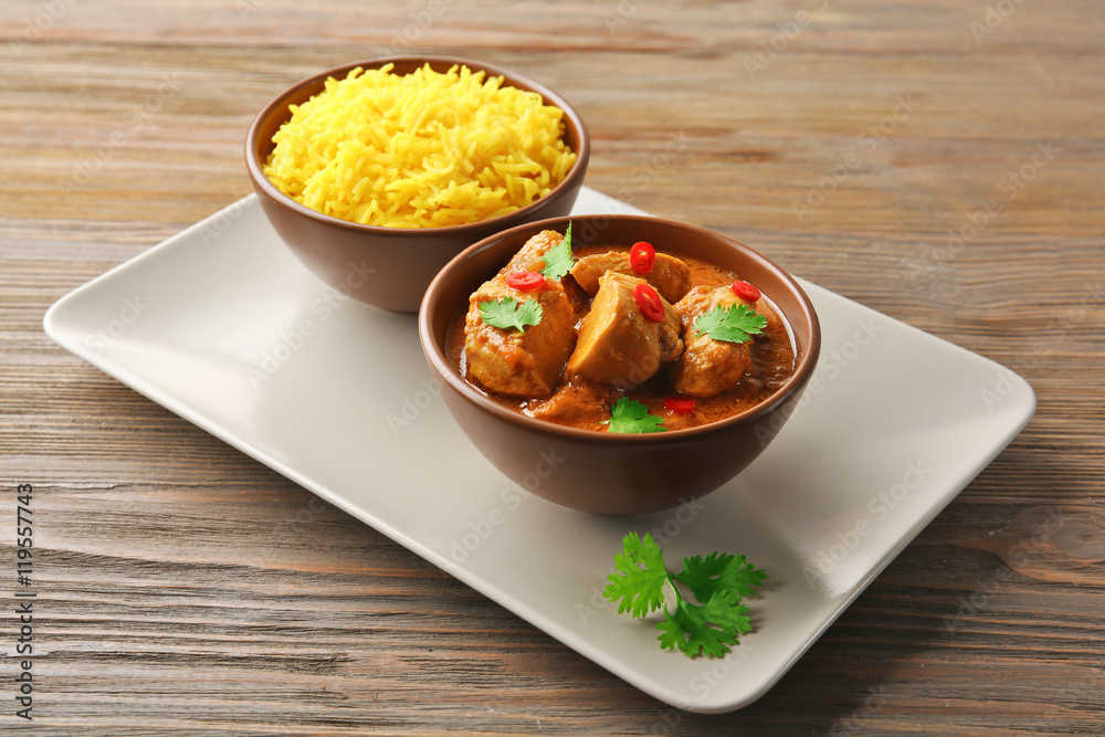 Tasty dinner with chicken curry in bowl on wooden background