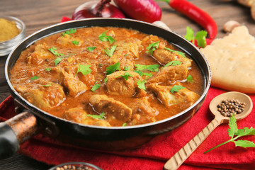 Poster - Tasty chicken curry in pan and spices on wooden background