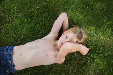 Portrait Of Boy Lying On Grass At Backyard