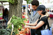 Multi-ethnic Couple Buying Vegetables At Market Stall