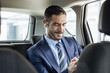 © Cavan Images - Smiling businessman listening music through earphones in car