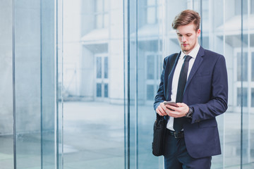 businessman using smartphone near office building