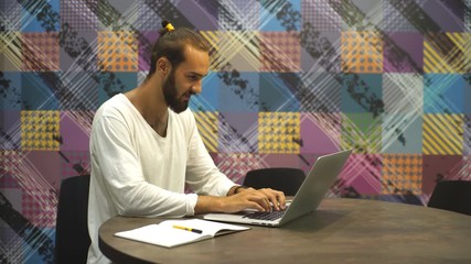 Young stylish man working in cafe with with laptop and notebook diary