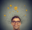 Excited man with many ideas light bulbs above head looking up