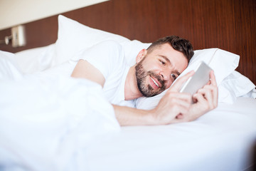 Wall Mural - Man texting his girlfriend in bed