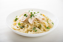 Pasta Fettuccine Alfredo With Chicken, Parmesan And Parsley On White Background Close Up. Italian Cuisine.